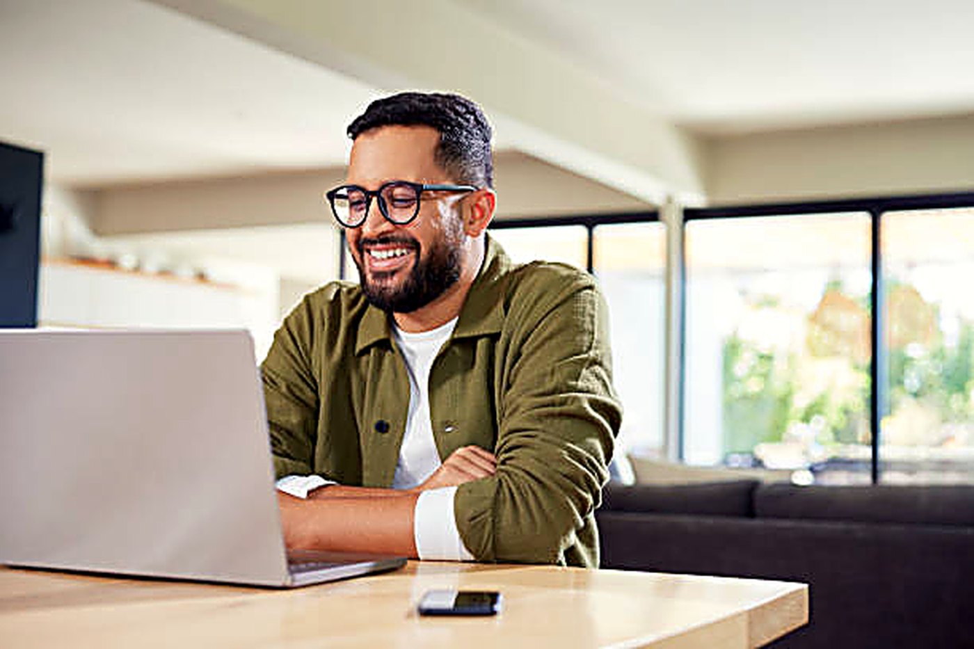 A man working at a laptop at home, mid-conversation